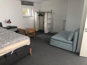 ein Schlafzimmer mit einem Bett, einem Sofa und einem Stuhl in der Unterkunft Familienfreundliches Ferienhaus Bahnstr 30C in Mainz