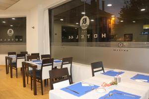 un comedor con mesas blancas y sillas con servilletas azules en Hotel 44, en Gijón
