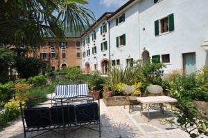 un patio con sillas, una mesa y un edificio en La Corte dei Limoni en Caprino Veronese