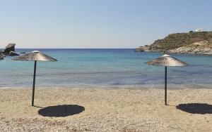 two straw umbrellas on a beach with the ocean at Demetra Waterfront House-Authentic Syros, by Elefthia Syros in Megas Gialos - Nites +6 photos