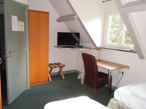Schlafzimmer mit einem Schreibtisch, einem Bett und einem TV in der Unterkunft Hotel Malcot in Mechelen