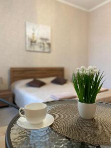 a table with a coffee cup and a vase with flowers at Family Apartment in Lviv