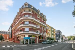 un gran edificio de ladrillo rojo en una calle de la ciudad en Zenitude Hôtel-Résidences Lorda en Lourdes