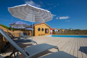 two chairs and umbrellas on a deck with a pool at Cabanas de Vendaval in Malpica