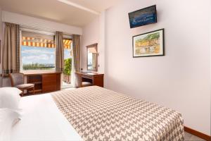 a hotel room with a bed, desk and a painting on the wall at Hotel Laurin in Santa Margherita Ligure