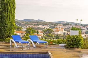 two blue chairs on a deck with a view of a city at Hotel Rec de Palau in Cadaqués