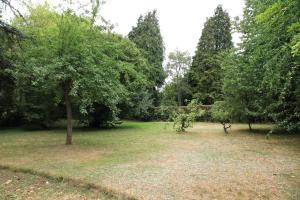 ein Park mit Bäumen und ein Feld mit Gras in der Unterkunft Normandie 12 couchages in LʼAigle