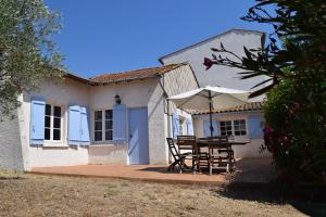 una casa con mesa, sillas y sombrilla en Hameau Montplaisir, en Béziers