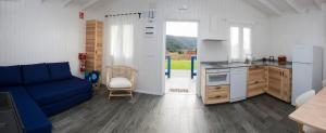 a living room with a blue couch and a kitchen at Cabanas de Vendaval in Malpica