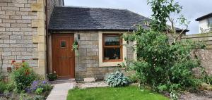a small house with a wooden door and a yard at Laburnum Cottage in Stirling