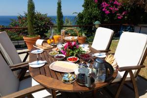 een houten tafel met eten en bloemen op een patio bij Villa Noria in Aghia Marina