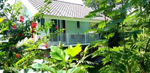une maison verte avec un balcon dans le jardin dans l'établissement บ้านอิงธารา โฮมสเตย์ ศาลายา Baan ing tara homestay salaya, à Salaya