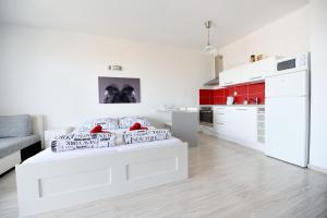 Biały pokój z łóżkiem i kuchnią w obiekcie Apartmán Centroom w Pieszczanach
