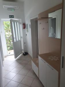 Apartments Jerković Drašnice-3bd في Drašnice: مطبخ مع دواليب بيضاء وباب الى ممر