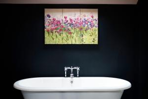 a bathroom with a painting above a white sink at The Westleton Crown in Westleton