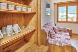 a room with a shelf with cups and a chair at Magnifique appartement aux Diablerets avec vue imprenable in Les Diablerets