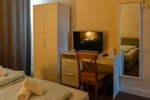 - une chambre avec un bureau, une télévision et un lit dans l'établissement G&H Hotel Rosengarten, à Rosengarten