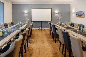 a conference room with tables and chairs and a whiteboard at G&H Hotel Rosengarten in Rosengarten