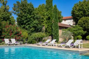 un gruppo di sedie a sdraio accanto alla piscina di Le Pré du Moulin - Maison Alonso - Hôtel & Restaurant a Sérignan-du-Comtat