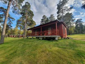a red cabin in the middle of a grass field at Gröna Uddens Camping in Mariehamn