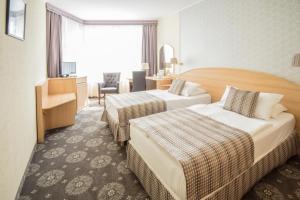 ブダペストにあるホテル オリオン ヴァールケールトのベッド2台とデスクが備わるホテルルームです。