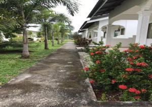 a sidewalk next to a house with red flowers at Alpha Motel in Pantai Cenang