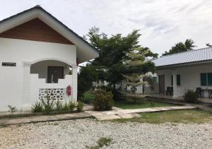 a white house with a red door and a yard at Alpha Motel in Pantai Cenang
