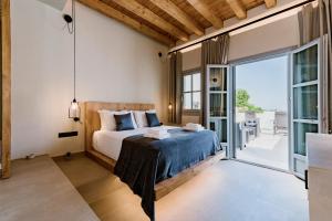 Lindos Calmare Suites في ليندوس: غرفة نوم بسرير وباب زجاجي منزلق