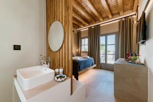 a bathroom with a sink and a mirror and a bed at Lindos Calmare Suites in Líndos