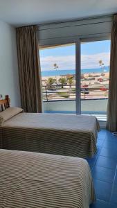 two beds in a hotel room with a view of the ocean at A. Garganta - Rocamaura & Catalonia in L'Estartit