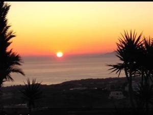 een zonsondergang met de zon die boven de oceaan opkomt bij Pansion Zaharoula in Fira
