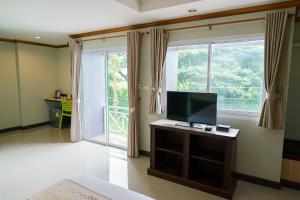 a bedroom with a tv and a large window at Thungtawan Hotel in Nakhon Si Thammarat