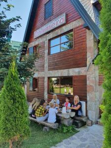 a group of people sitting at a table outside of a building at Holiday Home Vile Calimero in Žabljak