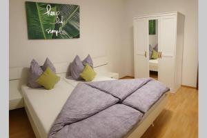 una camera da letto con un letto bianco con cuscini viola di Ruhige Ferienwohnung im Zentrum von Kempten a Kempten