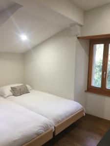 1 dormitorio con 1 cama blanca grande y ventana en La Dent-du-Midi Hôtel & Restaurant en Saint-Maurice