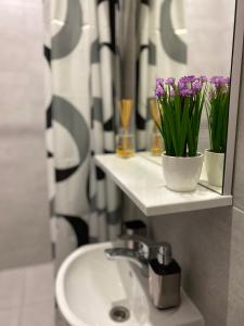 La salle de bains est pourvue d'un lavabo, d'un miroir et de fleurs violettes. dans l'établissement Homelike Apartment, à Lviv