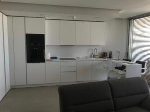 a kitchen with white cabinets and a couch in a room at The Edge Apartment in Estepona