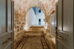 un pasillo con paredes de piedra y un arco en Lindos Calmare Suites en Lindos