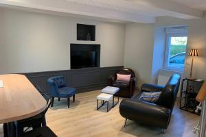 a living room with furniture and a flat screen tv at Robert's Family Petite Maison de Ville in Plancoët