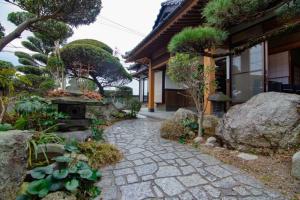 un jardín con una pasarela de piedra frente a una casa en 太宰苑 - Dazaien Traditional Japanese houses en Dazaifu