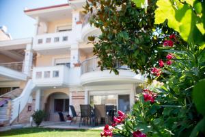 a large white building with chairs and pink flowers at Villa Verano in Asprovalta +39 photos