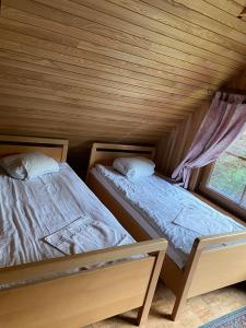 2 letti in una camera in legno con finestra di Šeimyninis namelis nr.1 a Kurėnai Altre 9 foto