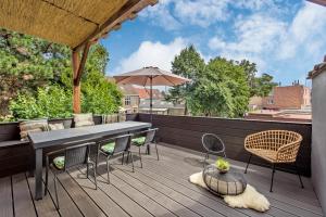 une terrasse avec une table, des chaises et un parasol dans l'établissement Beautifully renovated appt with big cosy terrace, à Knokke-Heist