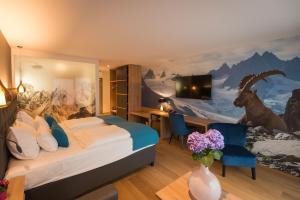 a room with a bed, a chair and a painting on the wall at Hotel dasMEI in Innsbruck