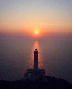 a lighthouse in the ocean with the sunset in the background at ALBA AD ORIENTE in Otranto