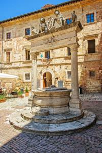 a stone building with a fountain in front of it at Meublè Evoè in Montepulciano
