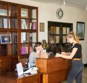 a woman sitting at a desk in front of a bookcase at Knyazha Hora Hotel in Kaniv
