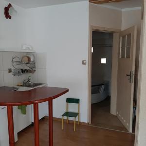 a kitchen with a table and a green chair at Apartament wolnostojący in Augustów