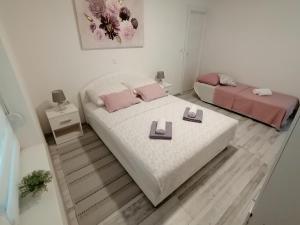 una camera con 2 letti con cuscini rosa di Apartman Lidija a Pag