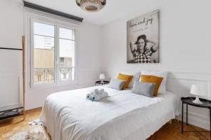 sypialnia z dużym białym łóżkiem z dwoma pluszakami w obiekcie Chic 1br near Paris and the Bois de Vincennes in Saint-Mandé Welkeys w mieście Saint-Mandé